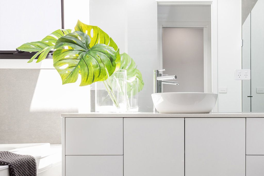 Badezimmer mit Monstera-Blättern in einer Vase